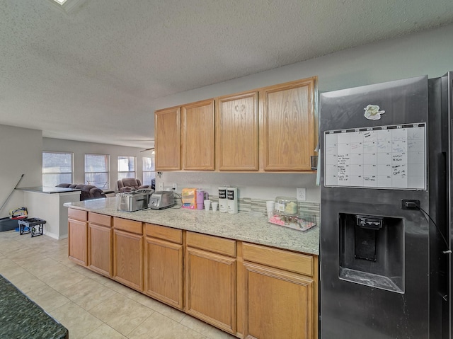 kitchen featuring light tile patterned floors, stainless steel fridge, light brown cabinets, and a textured ceiling