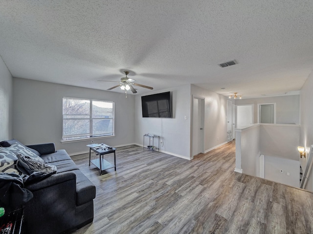 living room featuring ceiling fan, light hardwood / wood-style floors, and a textured ceiling