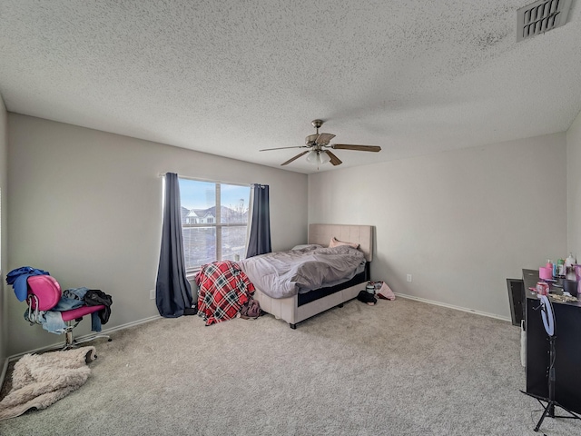 bedroom with ceiling fan, light carpet, and a textured ceiling