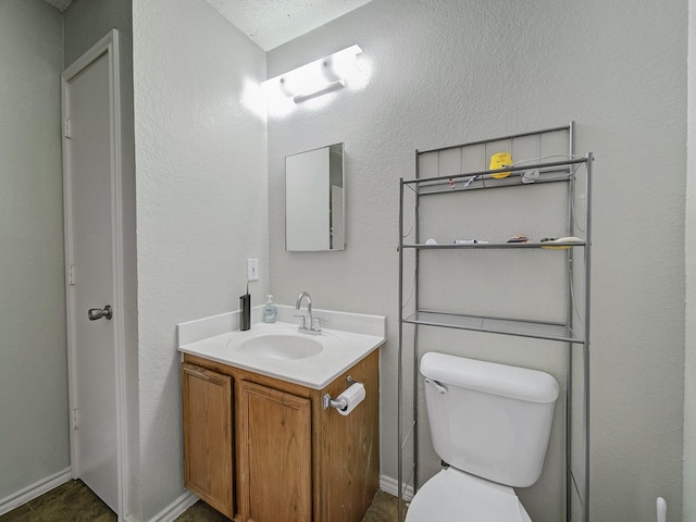 bathroom with toilet, vanity, and a textured ceiling