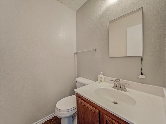 bathroom with hardwood / wood-style flooring, a textured ceiling, toilet, and vanity