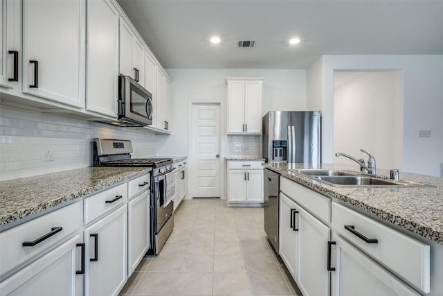 kitchen with white cabinets, appliances with stainless steel finishes, light stone countertops, and sink