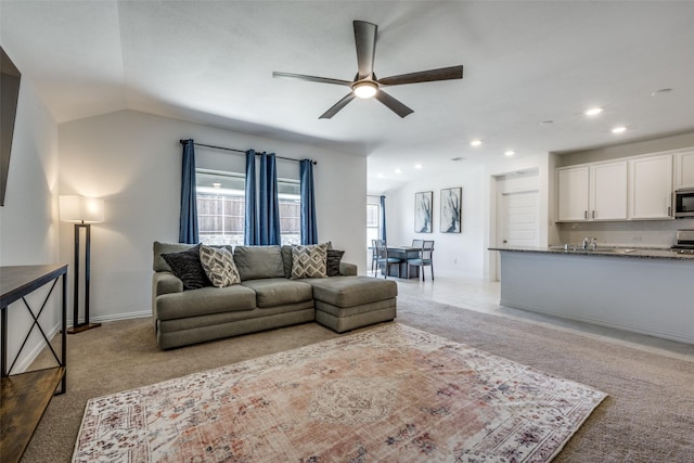 carpeted living room featuring ceiling fan and vaulted ceiling