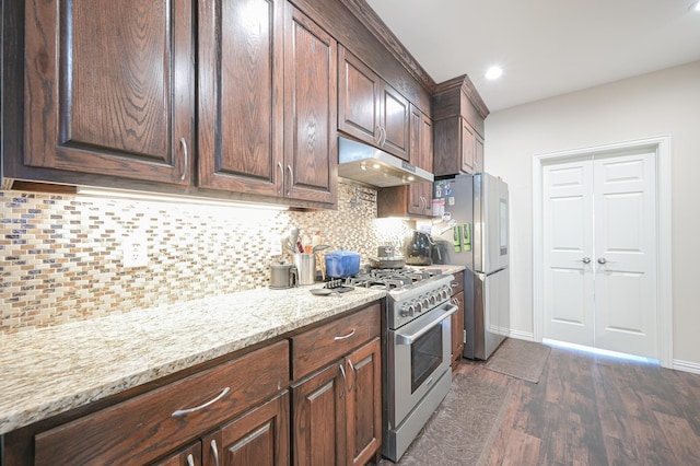 kitchen with dark hardwood / wood-style floors, light stone counters, dark brown cabinetry, and appliances with stainless steel finishes