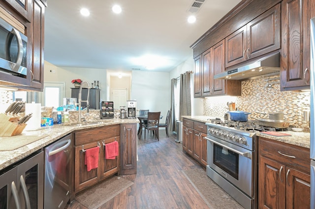 kitchen featuring sink, light stone counters, dark hardwood / wood-style flooring, stainless steel appliances, and beverage cooler