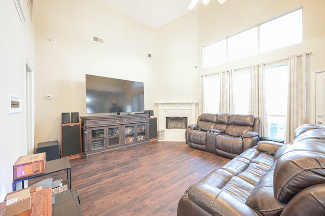 living room with a fireplace, a high ceiling, dark hardwood / wood-style flooring, and ceiling fan