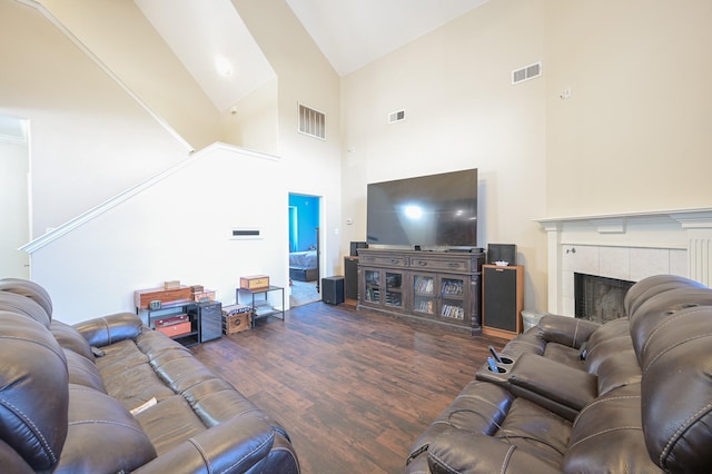 living room featuring a tile fireplace, high vaulted ceiling, and dark wood-type flooring