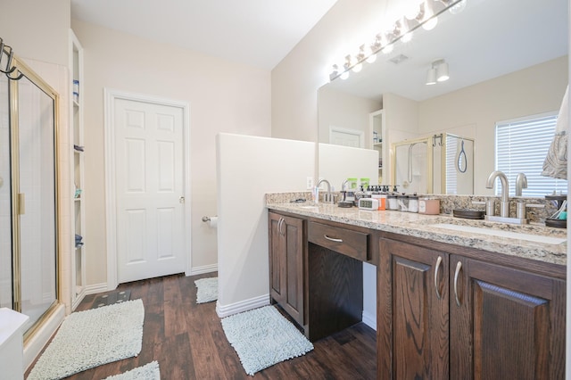 bathroom with wood-type flooring, vanity, and a shower with door