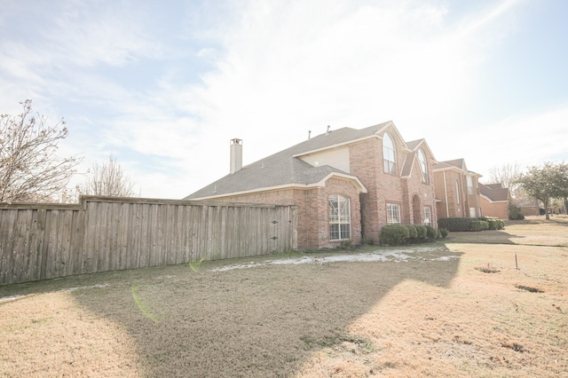 exterior space with brick siding, a chimney, and fence