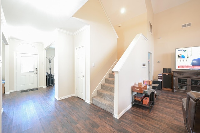 stairs with crown molding, hardwood / wood-style floors, and a towering ceiling