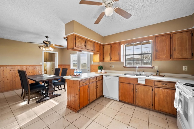 kitchen featuring white appliances, wooden walls, plenty of natural light, and sink