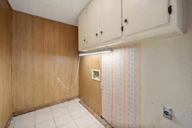 clothes washing area with a textured ceiling, cabinets, wooden walls, and electric dryer hookup