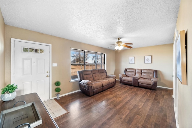 living room featuring dark wood-type flooring, a textured ceiling, and ceiling fan