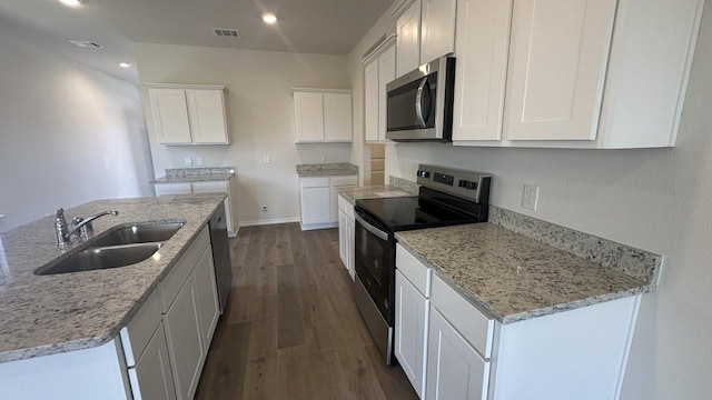 kitchen with white cabinets, stainless steel appliances, a center island with sink, and sink