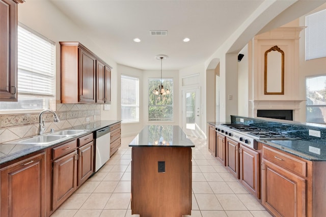 kitchen with backsplash, stainless steel appliances, sink, a notable chandelier, and a center island