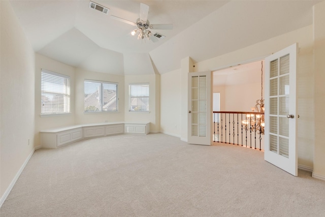 empty room with light carpet, french doors, ceiling fan with notable chandelier, and lofted ceiling