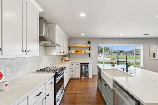 kitchen with white cabinets, wall chimney exhaust hood, light stone countertops, wine cooler, and appliances with stainless steel finishes