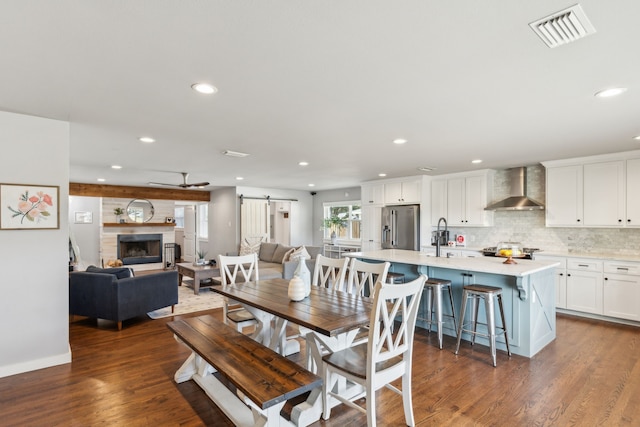 dining area with sink, a fireplace, a barn door, and dark wood-type flooring