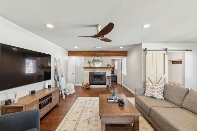 living room featuring wood walls, ceiling fan, a barn door, and dark hardwood / wood-style flooring