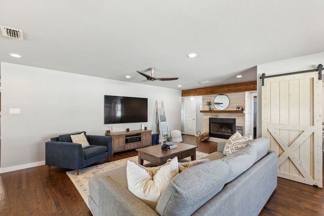 living room featuring ceiling fan, a barn door, and dark wood-type flooring