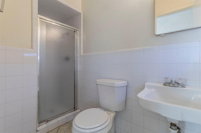 bathroom featuring toilet, tile walls, a shower with shower door, and sink