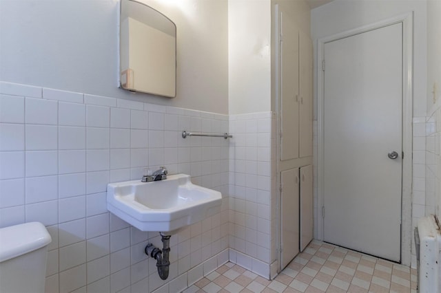 bathroom featuring tile patterned floors, toilet, radiator heating unit, and tile walls