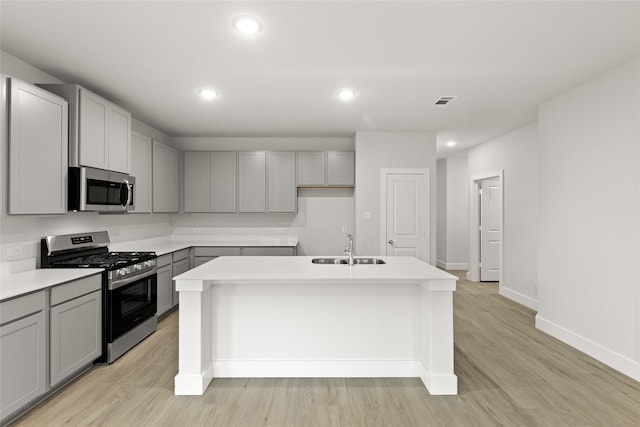 6721 Golden Grove Rd, Fort Worth, TX 76123 - kitchen featuring appliances with stainless steel finishes, gray cabinetry, a sink, a center island with sink, and light wood finished floors