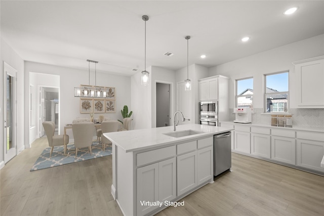 kitchen with pendant lighting, white cabinetry, sink, a kitchen island with sink, and stainless steel appliances