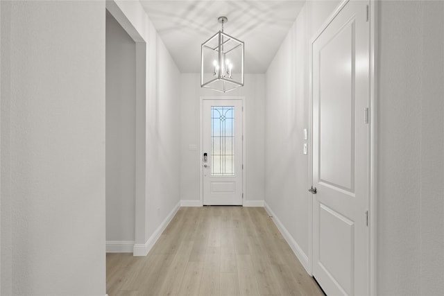 doorway to outside featuring a notable chandelier and light hardwood / wood-style flooring