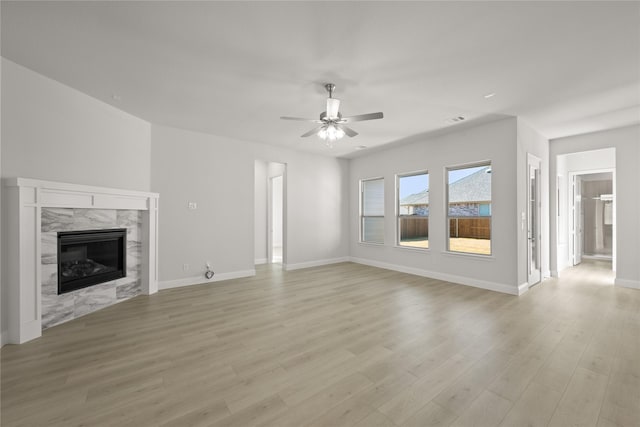 unfurnished living room featuring a premium fireplace, ceiling fan, and light hardwood / wood-style floors