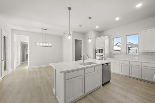 kitchen featuring a center island with sink, appliances with stainless steel finishes, hanging light fixtures, sink, and white cabinetry