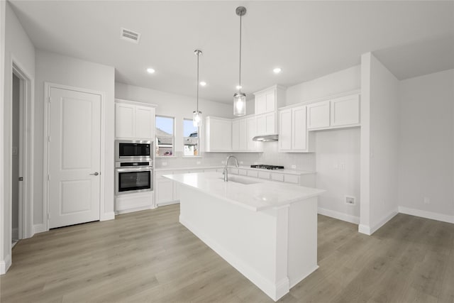 kitchen featuring stainless steel appliances, hanging light fixtures, a kitchen island, white cabinets, and backsplash