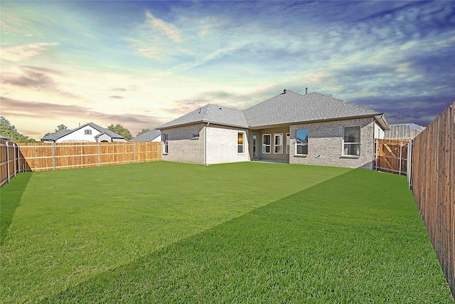 back house at dusk with a lawn