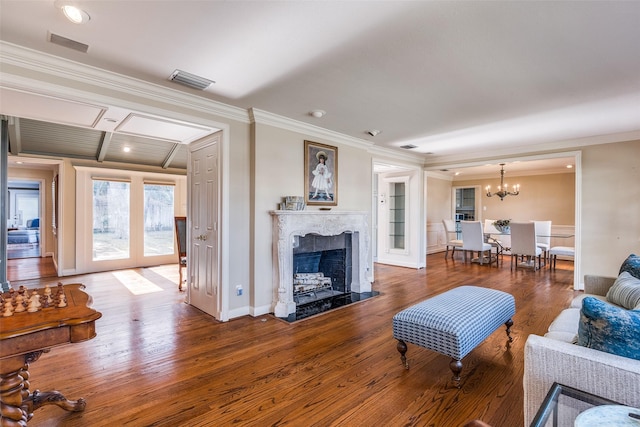 living room featuring a chandelier, crown molding, a high end fireplace, and wood-type flooring