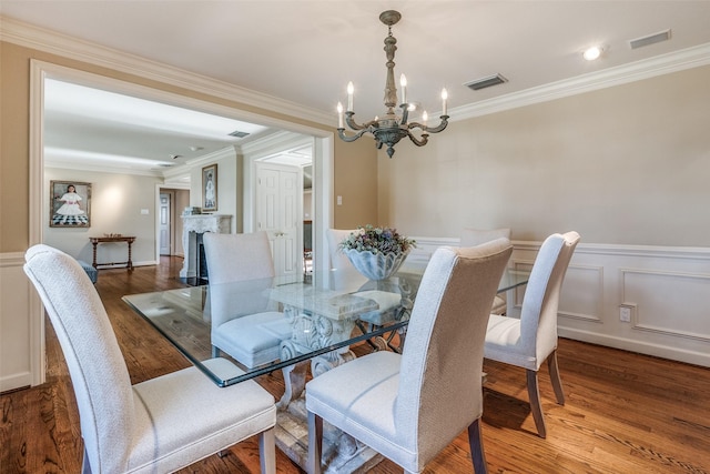 dining space with wood-type flooring, a notable chandelier, and ornamental molding