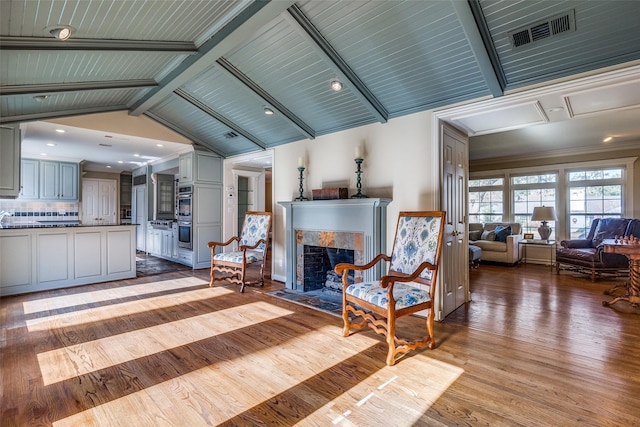 unfurnished living room featuring vaulted ceiling with beams, light hardwood / wood-style flooring, wood ceiling, and a tiled fireplace