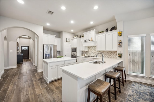 kitchen featuring sink, stainless steel appliances, a kitchen breakfast bar, kitchen peninsula, and white cabinets