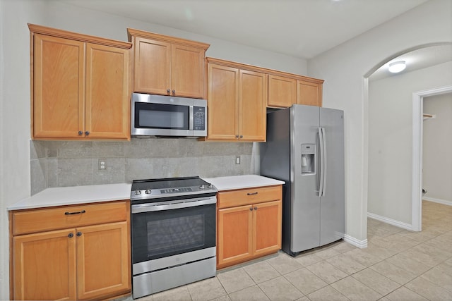 kitchen featuring light tile patterned floors, backsplash, and stainless steel appliances