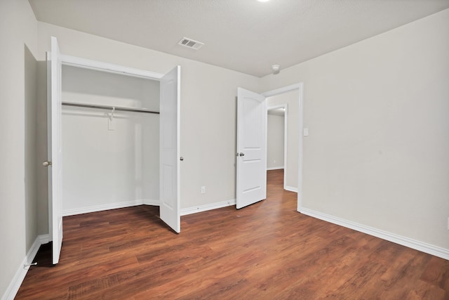 unfurnished bedroom with a closet and dark wood-type flooring