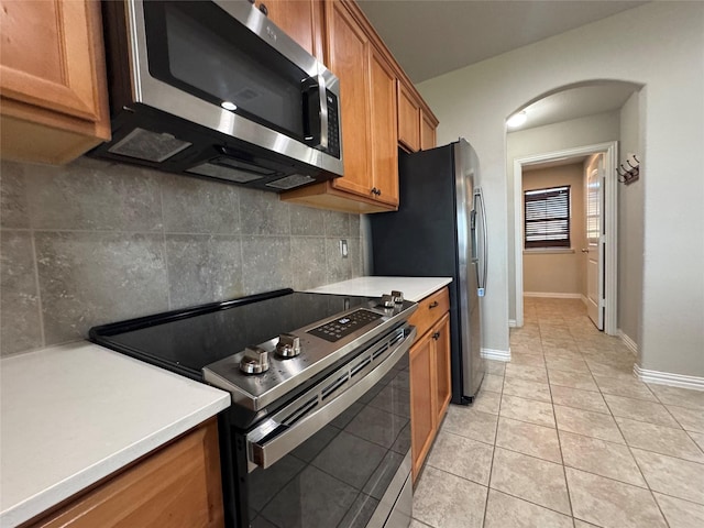 kitchen with light tile patterned floors, appliances with stainless steel finishes, and decorative backsplash