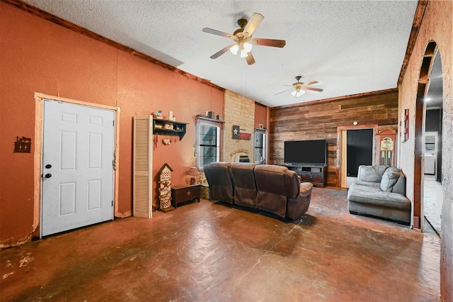 living room featuring wood walls, ceiling fan, concrete floors, and a textured ceiling