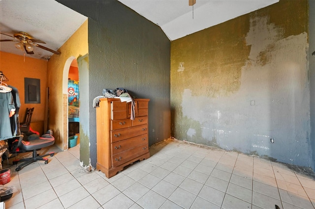 empty room with electric panel, ceiling fan, vaulted ceiling, and light tile patterned floors