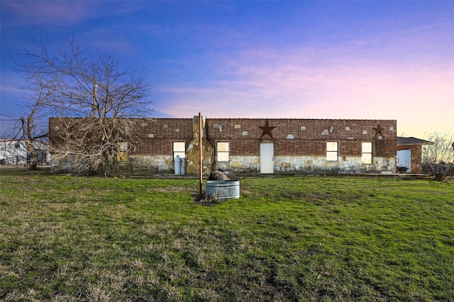 back house at dusk featuring a lawn