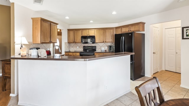 kitchen featuring backsplash, black appliances, light tile patterned floors, and kitchen peninsula