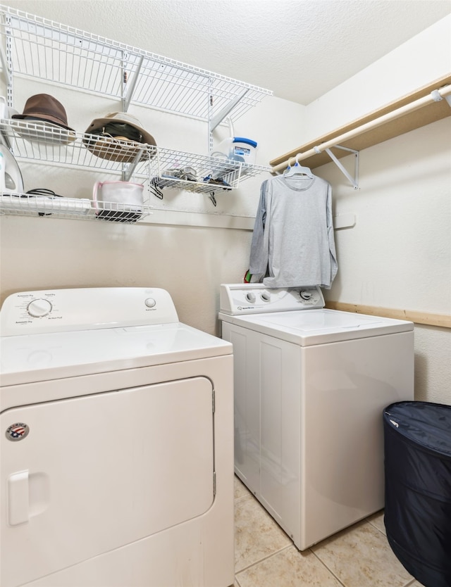 clothes washing area featuring washer and clothes dryer and light tile patterned floors