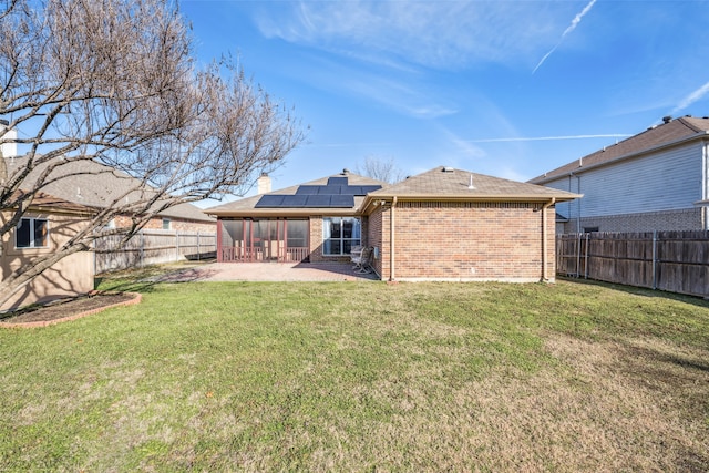 back of property featuring a lawn, a patio area, and solar panels