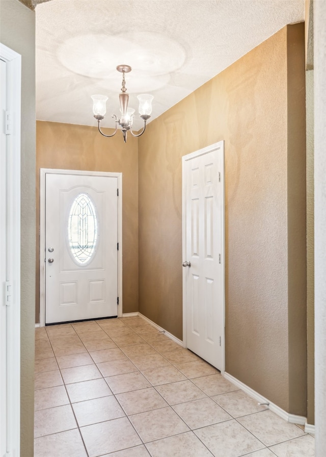 entryway with a textured ceiling, light tile patterned flooring, and a chandelier