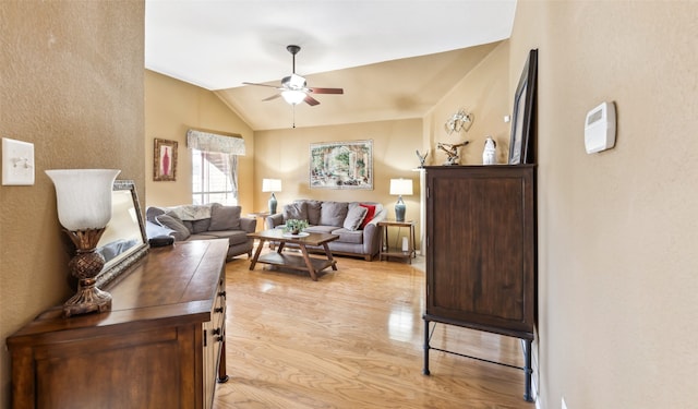 living room with ceiling fan, vaulted ceiling, and light hardwood / wood-style flooring