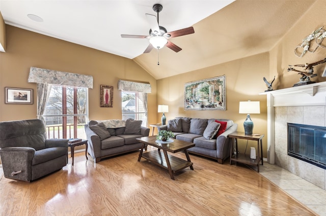 living room featuring light hardwood / wood-style floors, ceiling fan, vaulted ceiling, and a fireplace