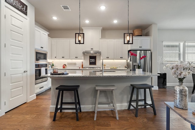 kitchen with white cabinets, stainless steel appliances, and a kitchen island with sink